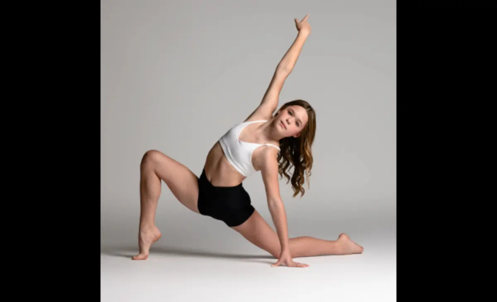 Private dance lessons in Blaine, MN represented by dancer wearing black and white dance outfit and doing a pose on the floor